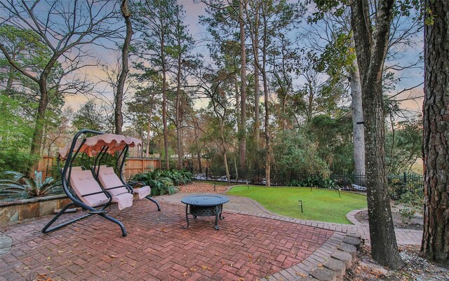 patio terrace at dusk featuring an outdoor fire pit and a lawn