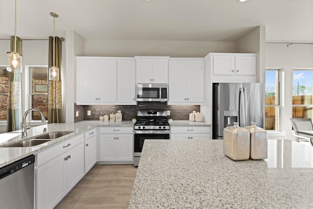 kitchen with appliances with stainless steel finishes, light stone countertops, sink, and white cabinets