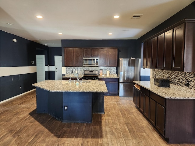 kitchen with a kitchen island with sink, stainless steel appliances, and light hardwood / wood-style floors