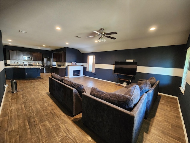 living room featuring vaulted ceiling, ceiling fan, and light hardwood / wood-style floors