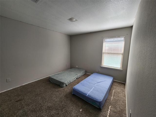 bedroom featuring a textured ceiling and dark colored carpet