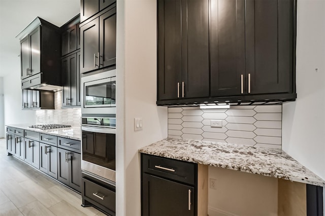 kitchen with stainless steel appliances, tasteful backsplash, and light stone countertops