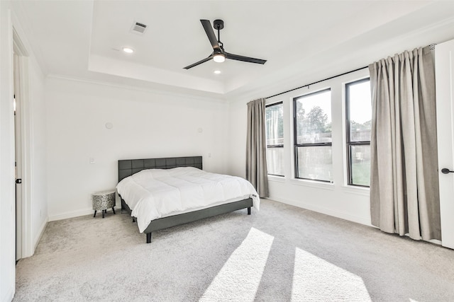 bedroom with multiple windows, a tray ceiling, and ceiling fan