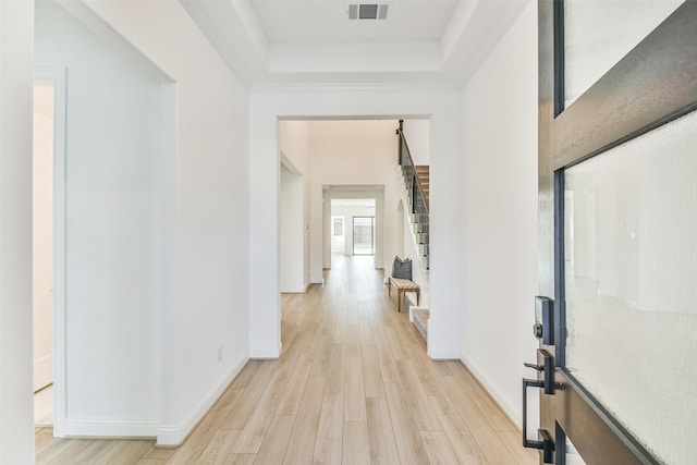 hallway featuring a tray ceiling and light wood-type flooring