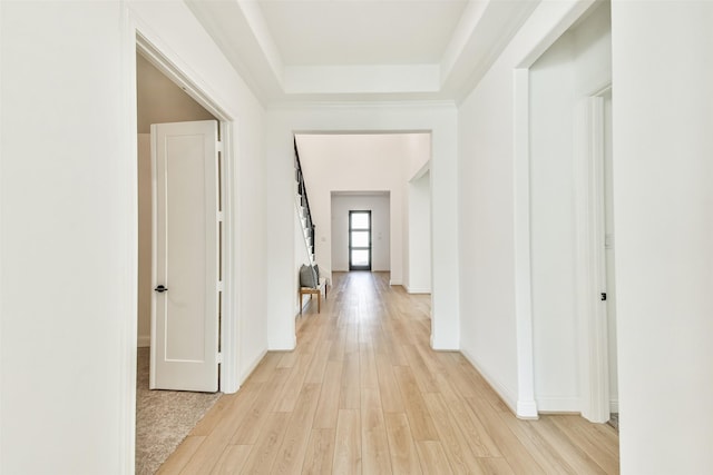 hallway featuring light wood-type flooring and a tray ceiling