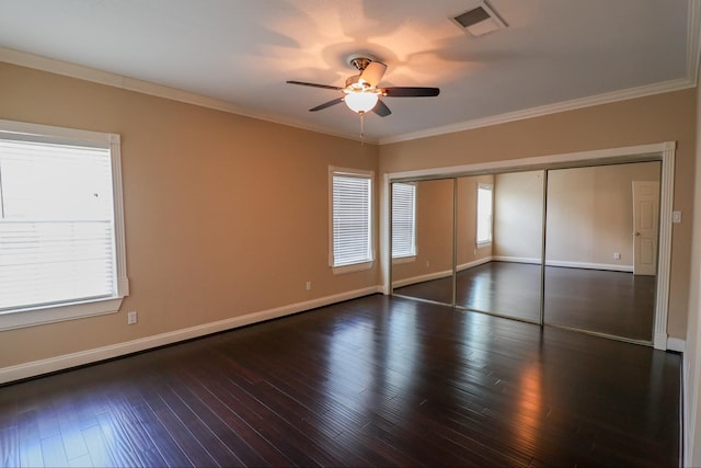 unfurnished bedroom featuring crown molding, ceiling fan, dark hardwood / wood-style flooring, and a closet