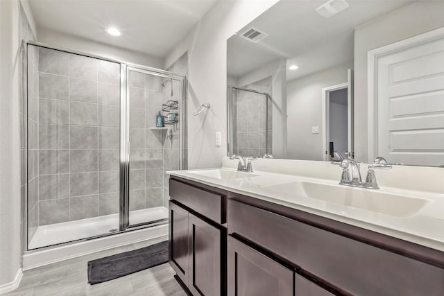 bathroom featuring a shower with door and vanity