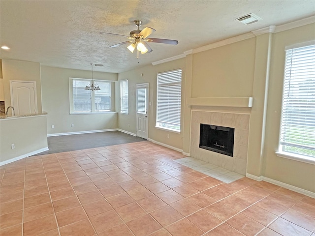 unfurnished living room featuring light tile patterned flooring, ceiling fan with notable chandelier, a fireplace, and crown molding