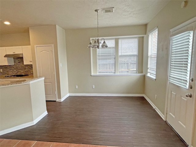 kitchen featuring decorative light fixtures, white cabinets, backsplash, light stone counters, and an inviting chandelier