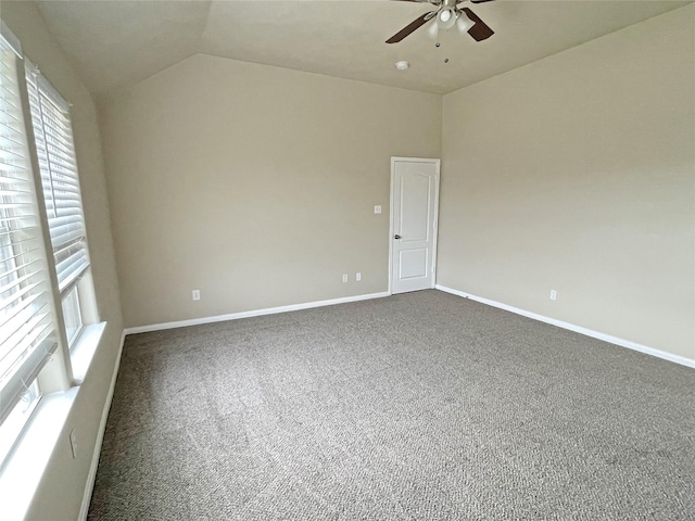 carpeted empty room with ceiling fan, vaulted ceiling, and a wealth of natural light