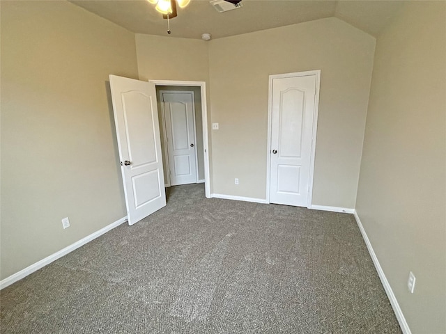 unfurnished bedroom with dark carpet and vaulted ceiling