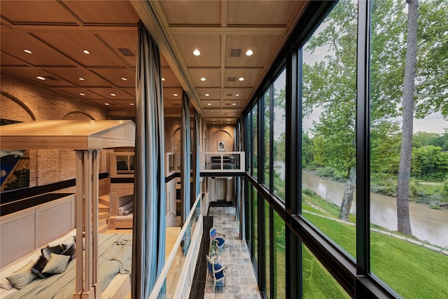 unfurnished sunroom featuring a water view, plenty of natural light, and visible vents