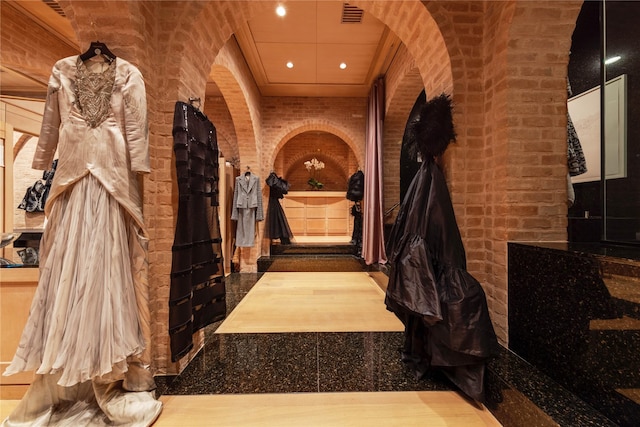 interior space featuring arched walkways, brick wall, visible vents, and recessed lighting