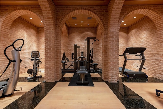 workout room featuring visible vents, brick wall, a towering ceiling, and recessed lighting