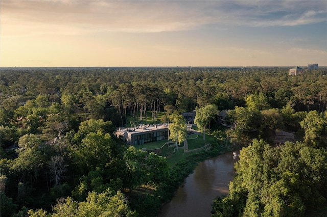 aerial view at dusk with a water view and a view of trees