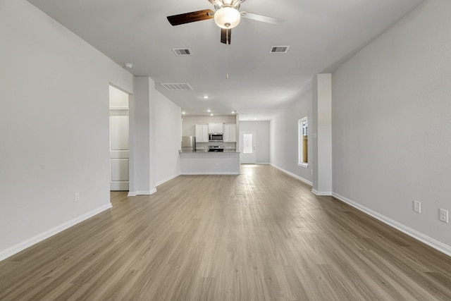 unfurnished living room with ceiling fan, baseboards, visible vents, and light wood-style floors