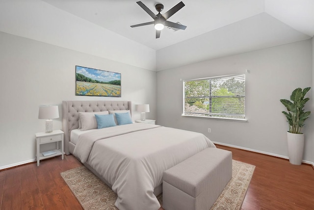 bedroom featuring vaulted ceiling, dark wood-type flooring, ceiling fan, and a tray ceiling