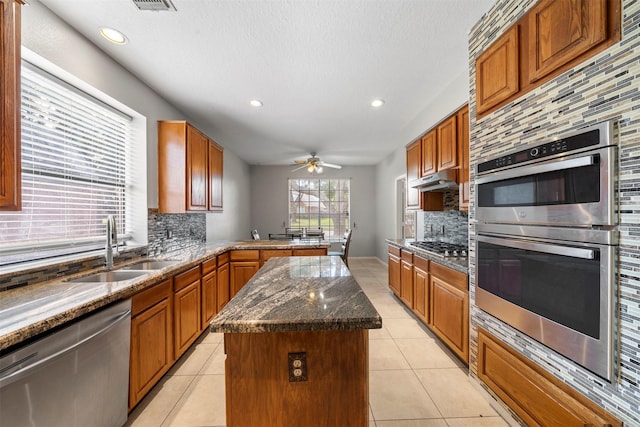 kitchen featuring light tile patterned flooring, a kitchen island, sink, backsplash, and stainless steel appliances