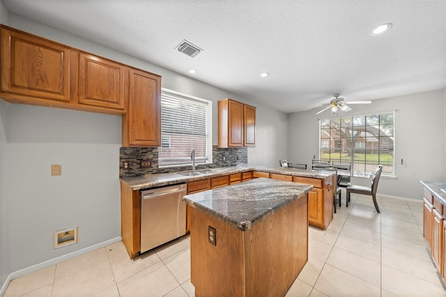 kitchen with sink, light tile patterned floors, dishwasher, backsplash, and a kitchen island