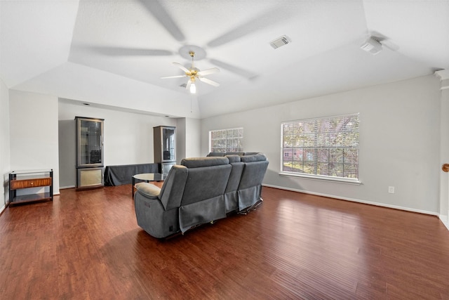 living room with lofted ceiling, dark hardwood / wood-style floors, a raised ceiling, and ceiling fan