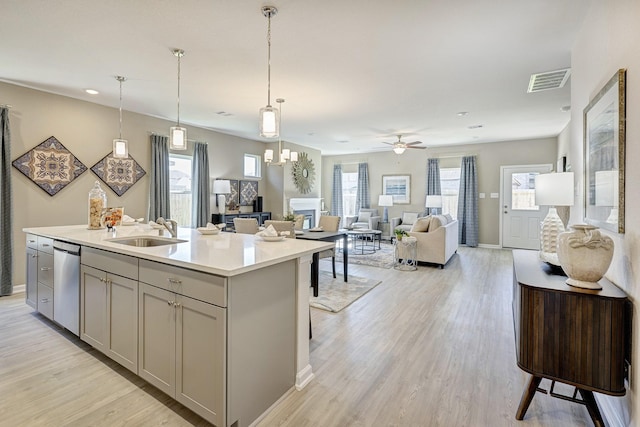 kitchen with sink, a breakfast bar area, ceiling fan, a kitchen island with sink, and stainless steel dishwasher