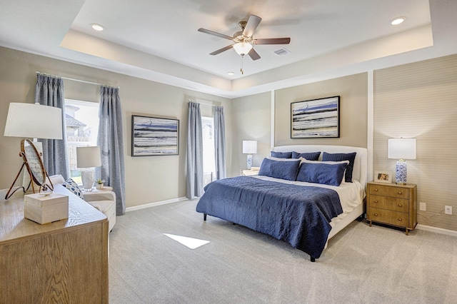 bedroom with a tray ceiling, light colored carpet, and ceiling fan