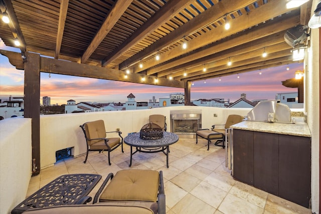 patio terrace at dusk with area for grilling and an outdoor fire pit