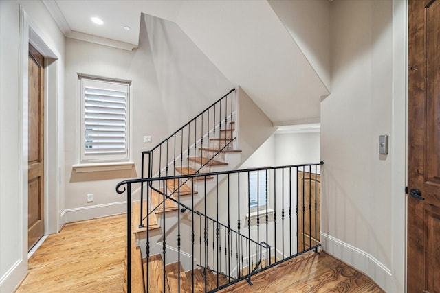 stairs featuring ornamental molding and hardwood / wood-style floors