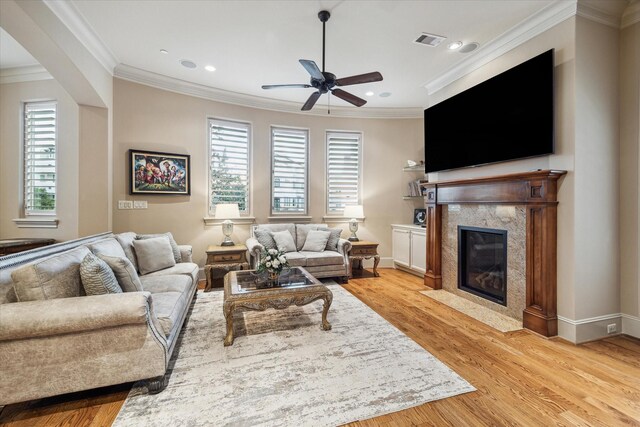 living room with crown molding, ceiling fan, a fireplace, and light hardwood / wood-style flooring