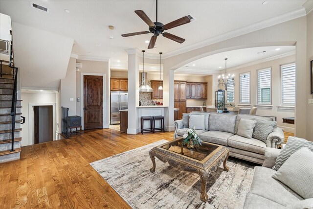 living room with crown molding, light hardwood / wood-style flooring, and ceiling fan with notable chandelier