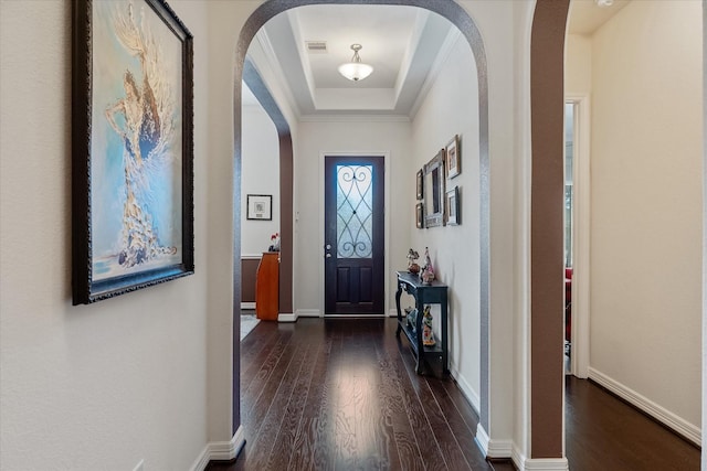 foyer featuring a raised ceiling, ornamental molding, and dark hardwood / wood-style flooring