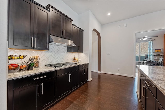 kitchen featuring stainless steel gas stovetop, tasteful backsplash, dark hardwood / wood-style flooring, light stone counters, and dark brown cabinets