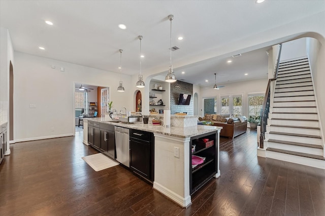 kitchen featuring hanging light fixtures, a center island with sink, stainless steel dishwasher, dark hardwood / wood-style floors, and light stone countertops