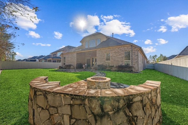 back of property featuring a fire pit and a lawn