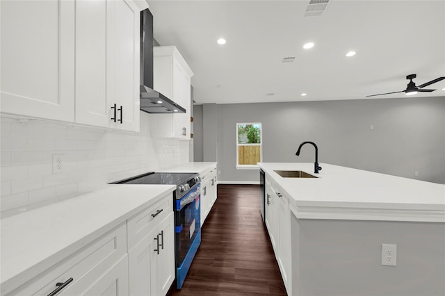 kitchen featuring electric range, white cabinets, wall chimney exhaust hood, light countertops, and a sink