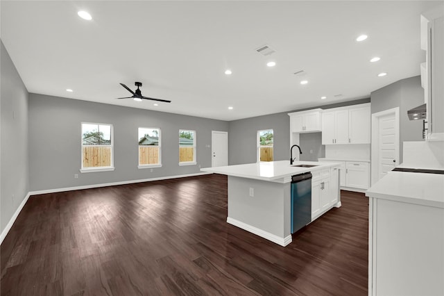 kitchen with a center island with sink, light countertops, visible vents, open floor plan, and white cabinets