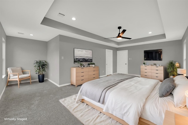 bedroom featuring ceiling fan, a raised ceiling, and light carpet