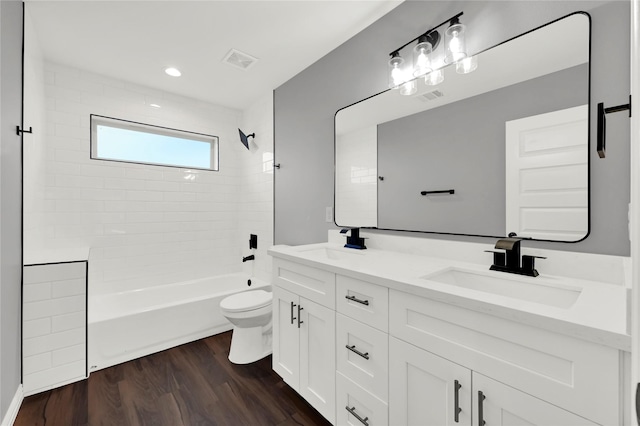 full bathroom with tiled shower / bath, hardwood / wood-style floors, vanity, and toilet