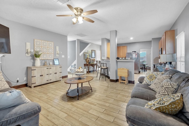 living room with ceiling fan and a textured ceiling