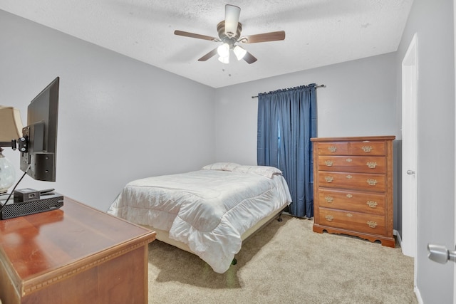 carpeted bedroom featuring ceiling fan and a textured ceiling