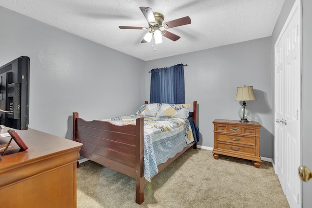 carpeted bedroom with ceiling fan, a closet, and a textured ceiling