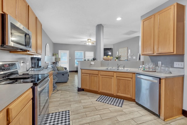 kitchen featuring stainless steel appliances, sink, light brown cabinetry, and ceiling fan