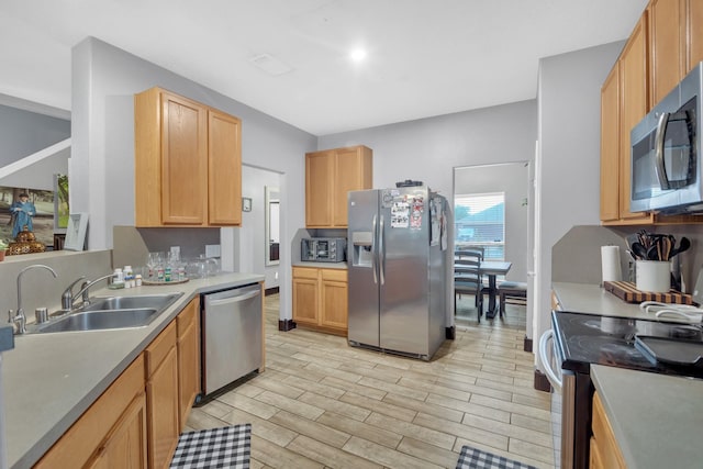 kitchen featuring stainless steel appliances, light brown cabinetry, and sink