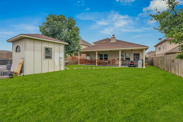 rear view of house with a wooden deck, ceiling fan, a storage shed, and a lawn