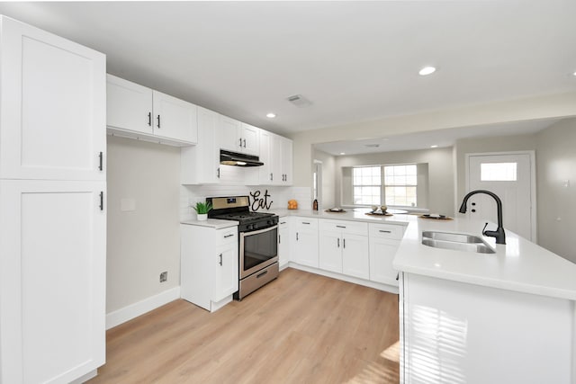 kitchen featuring sink, white cabinetry, light hardwood / wood-style floors, gas stove, and kitchen peninsula