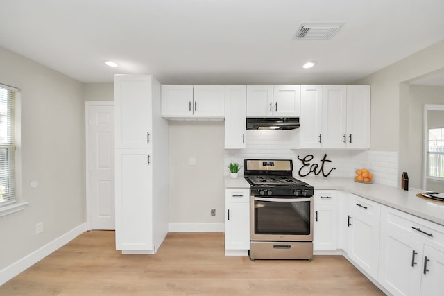 kitchen with tasteful backsplash, gas stove, light wood-type flooring, and white cabinetry