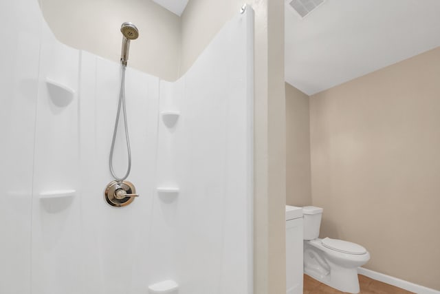 bathroom with a shower, tile patterned floors, and toilet