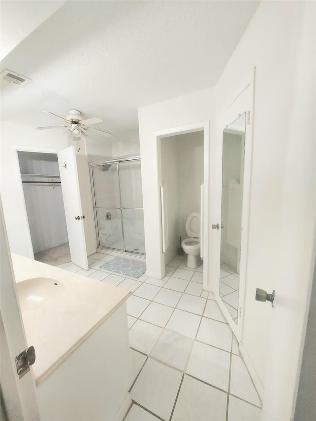 bathroom featuring toilet, vanity, a shower with door, ceiling fan, and tile patterned flooring