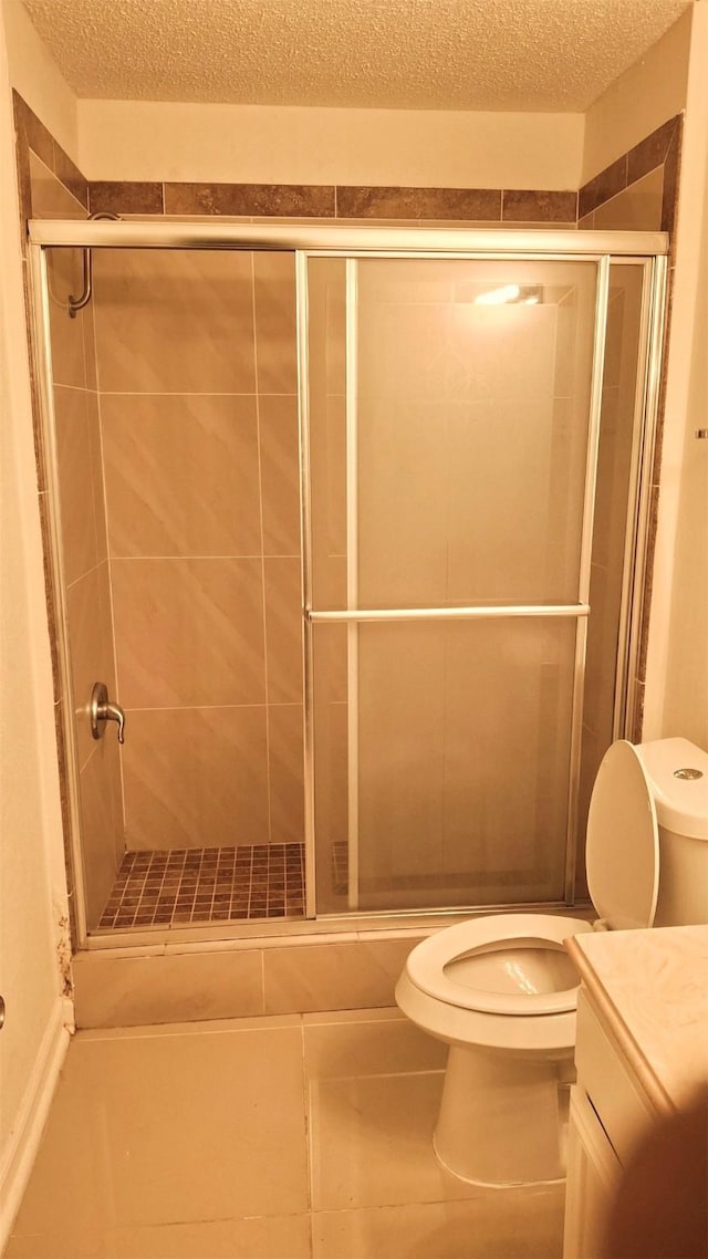 bathroom with a shower with door, vanity, tile patterned flooring, and toilet