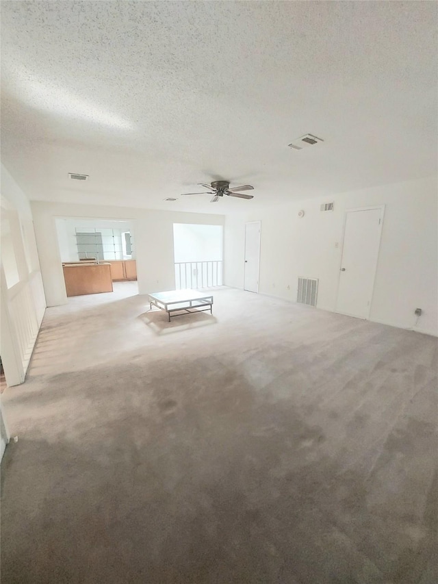 carpeted spare room with ceiling fan and a textured ceiling